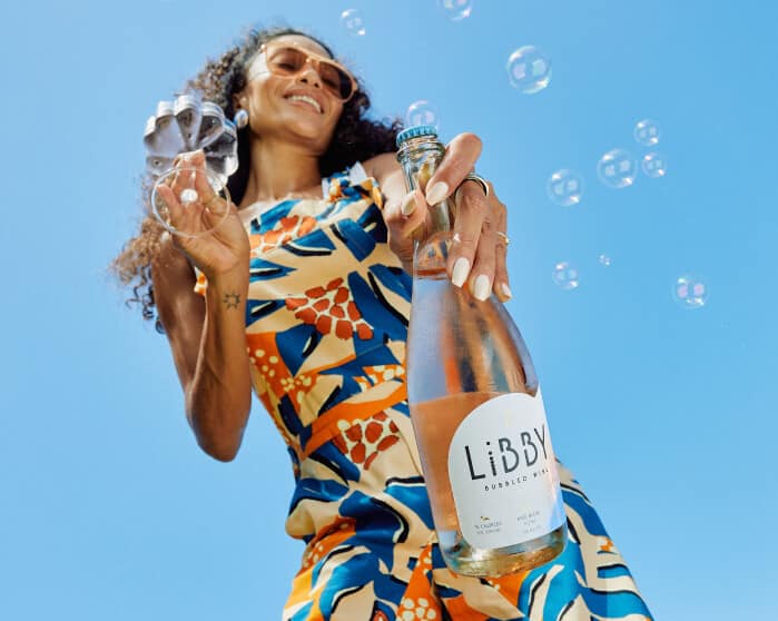 Libby woman holding bottle and glass with bubbles