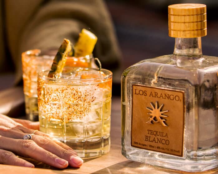 Los Arango Tequila hand holding cocktail near bottle