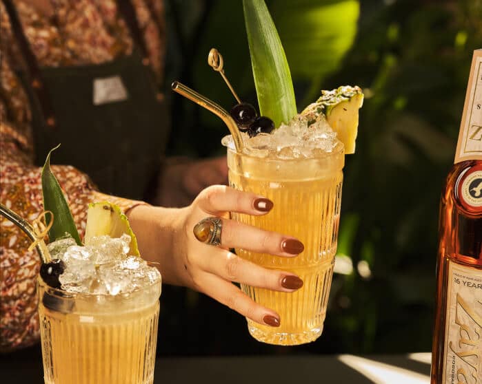 Zaya rum cocktail in hand being served with pineapple